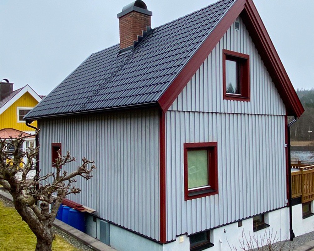 Bild på svarta betongpannor på ett grått hus