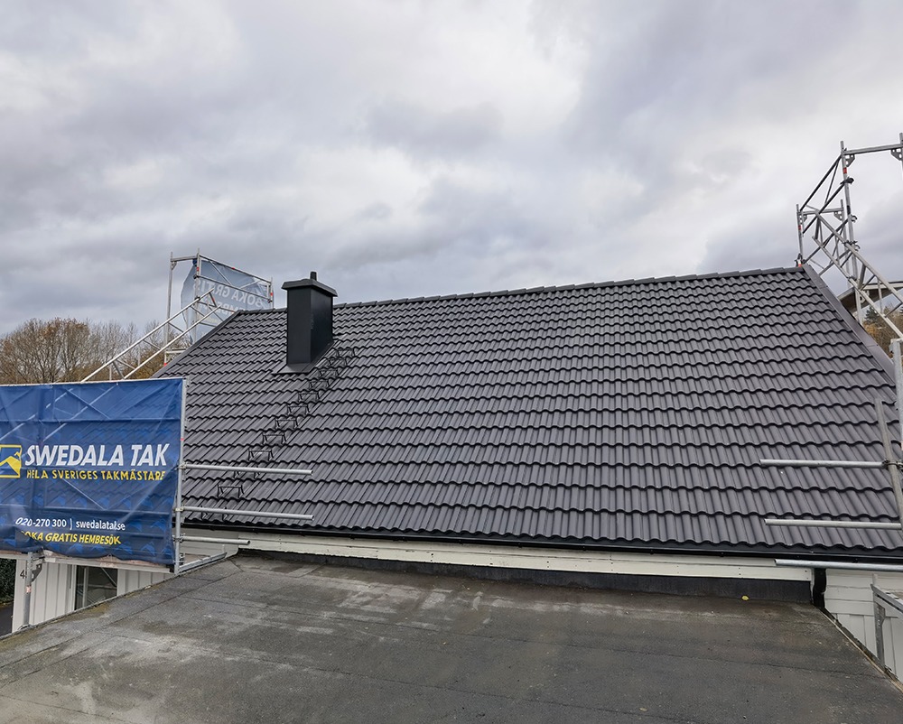Bild på tak med svarta betongpannor och byggställning