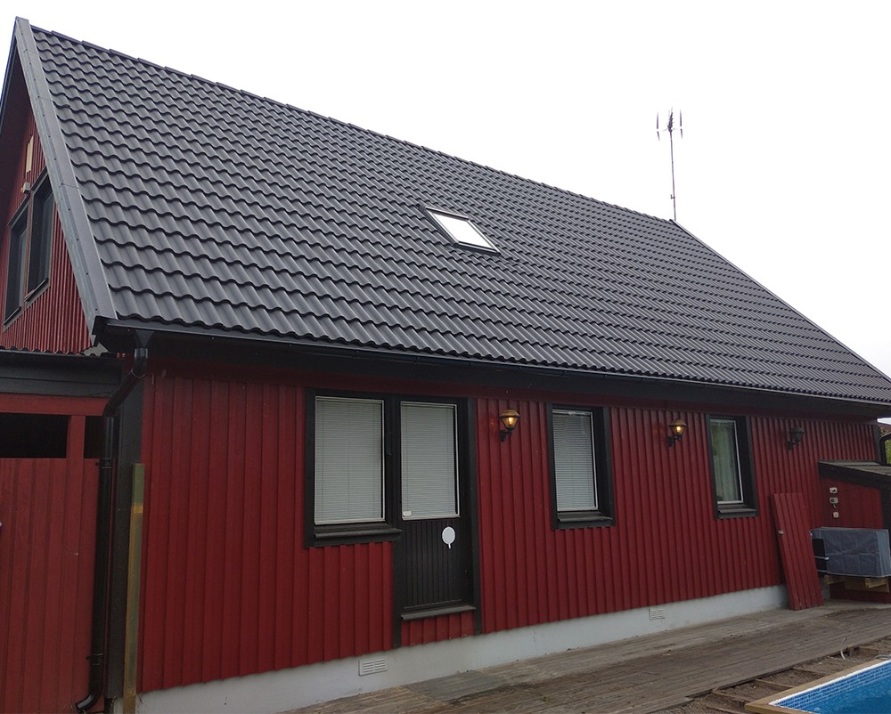 Svart tak med betongpannor är snyggt på ett rött hus