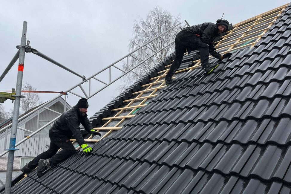 Två personer lägger nytt tak på en villa i Ljusdal.