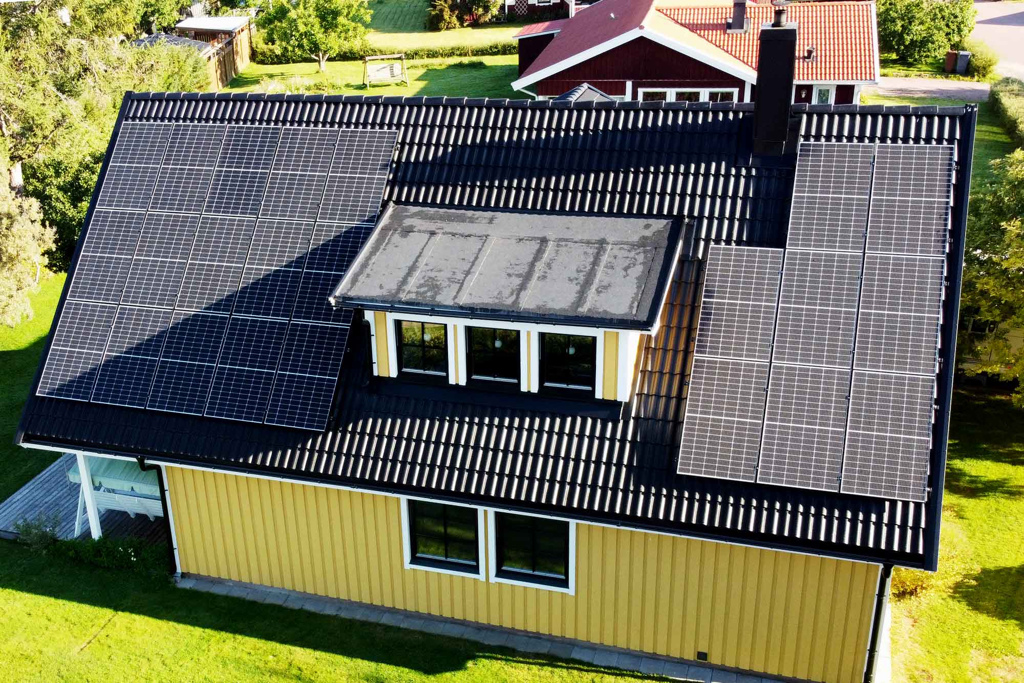 Gul fasad, svarta takpannor och solceller som snyggt smälter in!