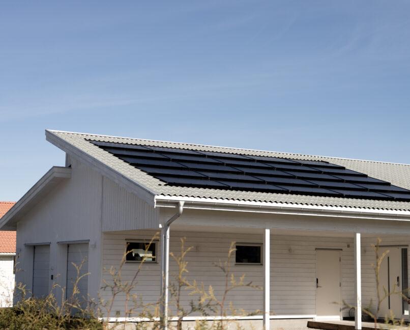 Vitt hus i solljus med integrerat solcellstak.